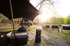 Black Heavy Duty Tarpaulin shelter setup by a river at sunset.